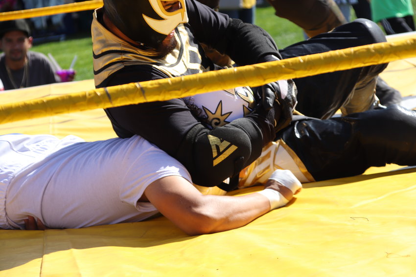 Luchadore Anubis menaces rival Rey Virgo with a headlock Oct. 2 at Thornton's Harvest Fest. Luchadores from Hugo's Lucha Libre performed several exhibition matches like this during the festival.